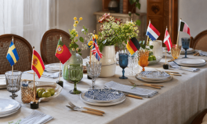 Mesa decorada con vajillas europeas y banderas de países en estilo Eurovisión