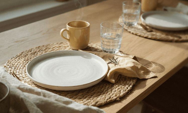 Detalle de una mesa mediterránea con lino, cerámica artesanal y pequeños toques en amarillo mantequilla.