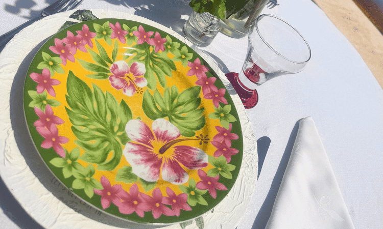Detalle de una vajilla estampada con flores tropicales sobre un bajoplato blanco